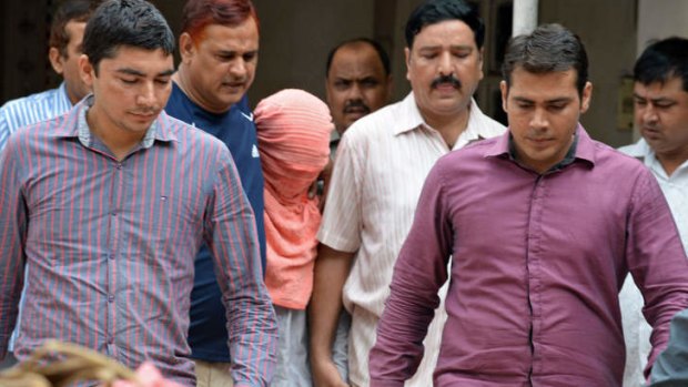 Indian policemen escort the juvenile in pink hood, accused in the December 2012 gang-rape of a student, following his guilty verdict at a court in Delhi.