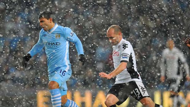 Manchester City's Sergio Aguero takes possession ahead of Fulham's Danny Murphy in wintry conditions at Etihad Stadium.