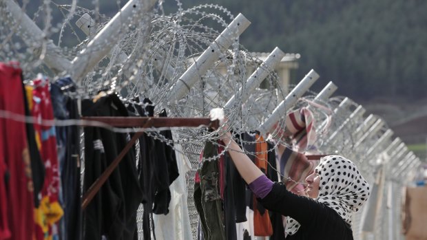 A Syrian woman hangs clothes to dry at a Turkish camp for refugees.