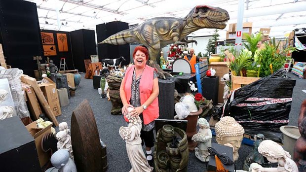 Chaos: Helen Christodoulou of Gardenhouse Decor sorts out her exhibit, with an animatronic dinosaur in the background.