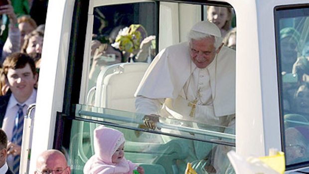 The Pope blesses a baby as her arrives at Glasgow's Bellahouston Park.