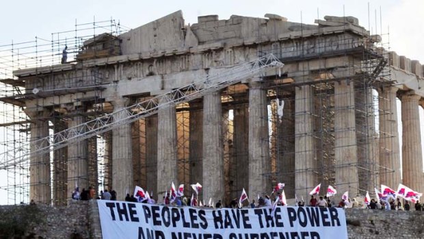 Fly the flag ... the Greek communist group PAME unfurls a banner at the Acropolis. Public anger over government austerity measures continues.