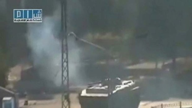 Scores reportedly dead ... smoke is seen near a tank at Al-Bahra roundabout in Hama.