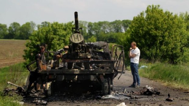 Locals near remains of a Ukrainian truck-mounted canon, destroyed when pro-Russian rebels attacked the Ukrainian military, killing seven soldiers and wounding eight in Dmitrievka, East Ukraine. 