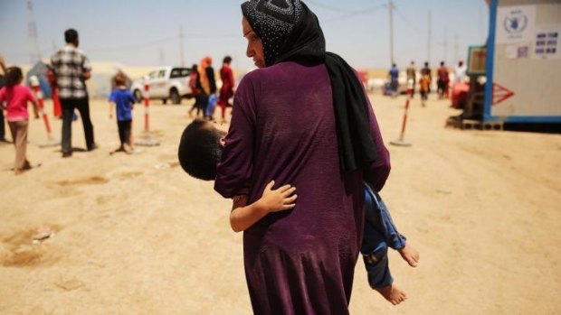 Iraq lost 2417 in June: An Iraqi woman holds her exhausted son as they flee fighting around Mosul.