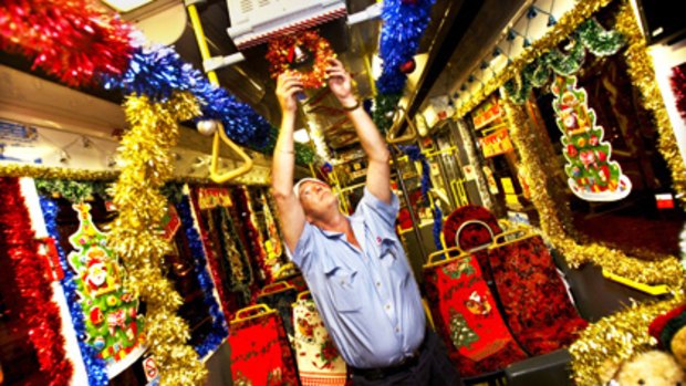 Santa Claus is coming to Circular Quay ... driver Barry Ridley decorates his bus at the Kingsgrove Depot. Below: driver Linda-Ann Montuori is sometimes called ‘‘Mrs Claus’’ by passengers.