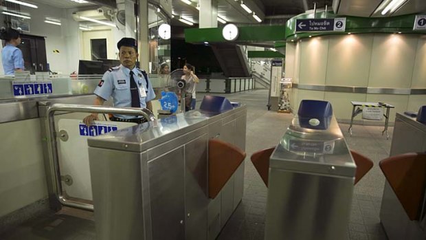 A Thai security guard stands at the entrance to the Bangkok Skytrain after it closed at 9pm stranding thousands of people as they headed home.