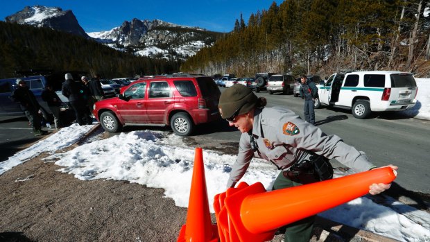 Park Ranger Amy Fink place pylons in the parking lot for the Bear Lake trail in Rocky Mountain National Park on Saturday. Despite a government shutdown, Rocky Mountain National Park in Colorado and Yosemite National Park in California were open, but few Park Service staff were available to help visitors. 