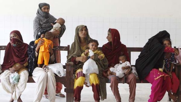 Troubled waters ... mothers and children wait to be seen at a hospital in Mazaffargarh district. Weeks of flooding have badly strained Pakistan?s medical system.