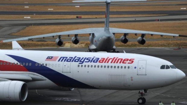 Mystery: A Malaysia Airlines plane prepares to go onto the runway and pass by a stationary Chinese Ilyushin 76 search aircraft (top) at Perth International Airport. 