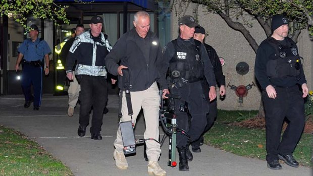 Police and federal officials exit an apartment complex in a Boston suburb.