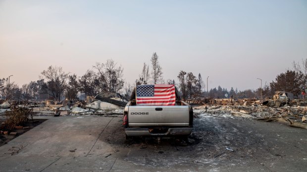 An American flag is taped on the back of a pick up truck standing in front of residences burned by wildfires in Santa Rosa, California.