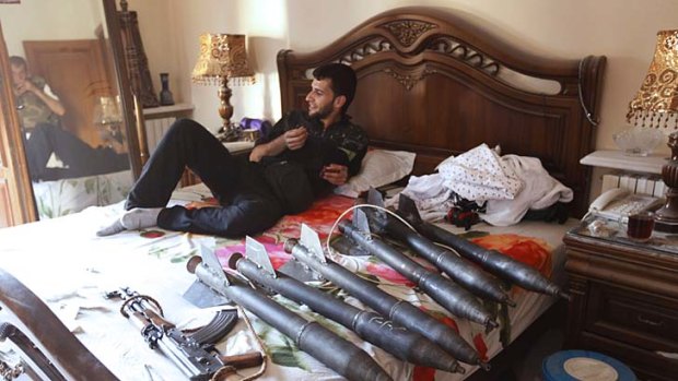 A member of the Free Syrian Army relaxes on a bed next to weapons inside a house in Aleppo.