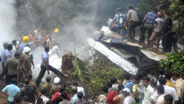 Onlookers and firefighters stand at the site of the crashed Air India Express passenger plane in Mangalore.