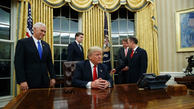 Vice President Mike Pence (left) watches as President Donald Trump prepares to sign his first executive order.