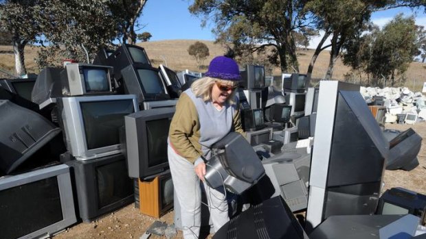 Dawn Richardson, of Curtin, places her old analog  television set  into the pile at the Mugga Lane tip.