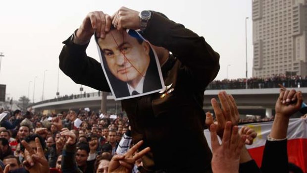 An anti-government protester tears up a picture of Egyptian President Hosni Mubarak.