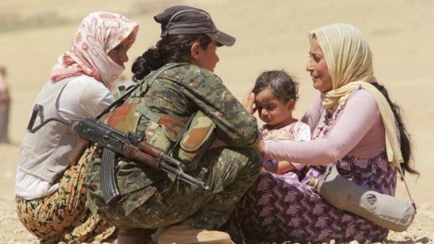 Displaced people from the minority Yazidi sect speak with a Kurdish fighter near the border between Iraq and Syria's Hasaka province last month.