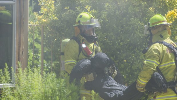 Firefighters carry a dummy out of the house.