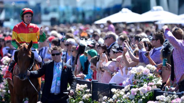 In the picture: Race goers at Flemington take photos of jockey Damien Oliver on Happy Days at Emirates Stakes Day during last year's spring racing carnival.