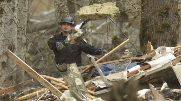 Massive task ... A worker throws debris while looking for victims in the mudslide near Oso.