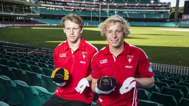 History in their hands: Callum Mills and Isaac Heeney hold  premiership caps from 1888 and 1889, and premiership medals from 1933 and 1918, which were donated to the Sydney Swans Foundation.