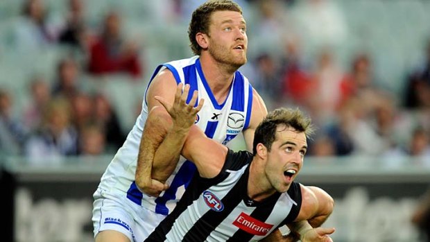 Collingwood's Steele Sidebottom battles with North's Lachlan Hansen.