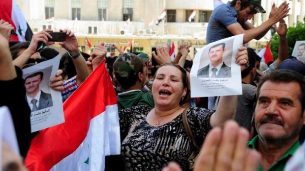 Syrian demonstrators wave portraits of the President, Bashar al-Assad on Monday.