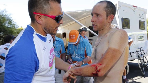 Blood and sweat ... Matt Lloyd has his wounds treated by the Lampre-Merida team doctor following a crash on stage two.