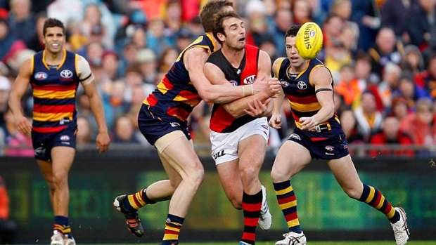 Under pressure: Jobe Watson is chased down by Adelaide players.