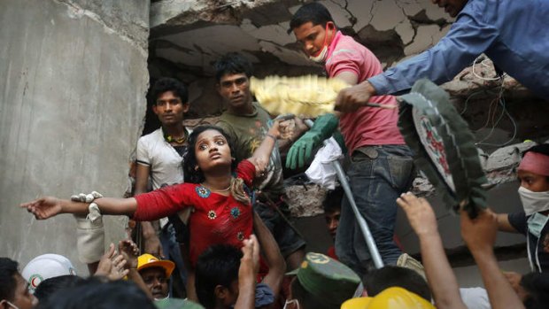 Alive: A survivor is lifted out of the rubble by rescuers on Thursday.