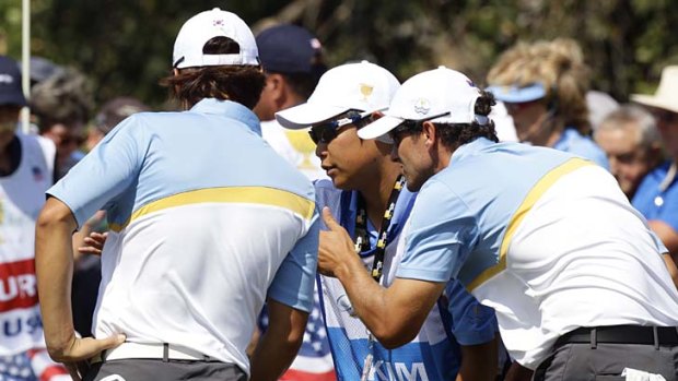 This way: Adam Scott (right) tries to explain the lie of the green to Kyung-tae Kim via his partner's caddie (centre).
