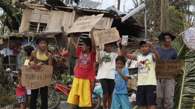 Children hold signs asking for help and food along the highway, after Typhoon Haiyan hit Tabogon town in Cebu Province, central Philippines.