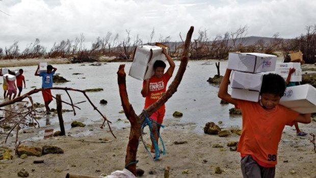 Locals carry aid packages after Cyclone Haiyan.