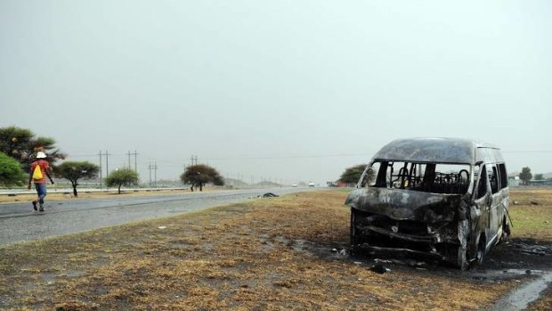 Unrest .... A man passes a burnt-out minibus taxi near the Amplats mine, where two men were killed.