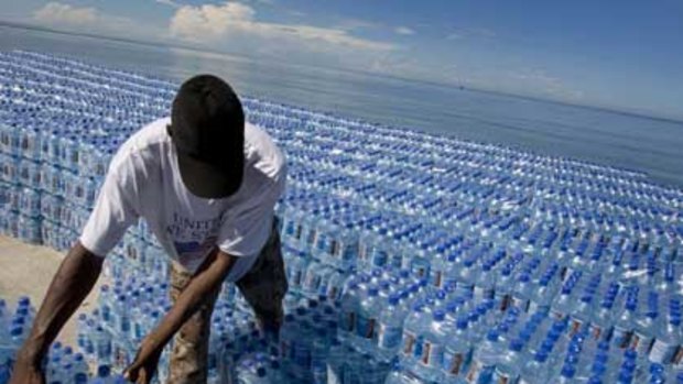 A Haitian man unloads water donated by the World Food Program after Tropical Storm Hanna passed through the region, dumping heavy rains that flooded region and claimed at least 136 dead.