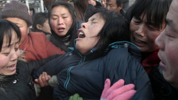 Cry from the heart... the relative of a miner killed in a pit gas explosion breaks down as others gather for news outside the entrance to XingXing coalmine.