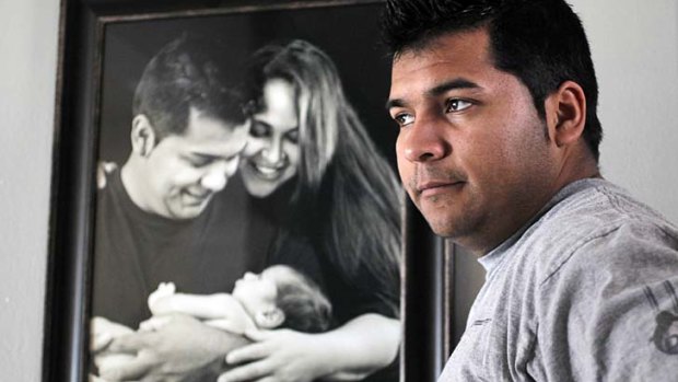 Marlise Munoz's husband Erick stands in front of a family portrait of the couple with their son Mateo.