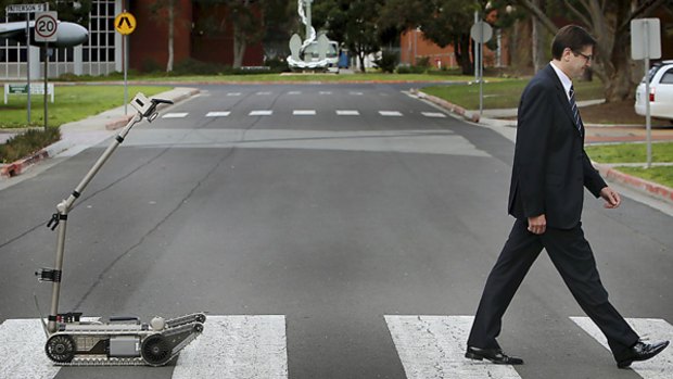 Minister for Defence Personnel Greg Combet  is followed by a  Packbot.