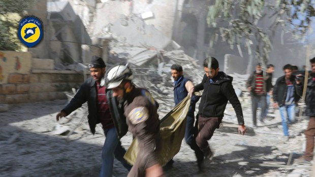 This photo provided by the Syrian Civil Defense White Helmets shows Civil Defense workers and Syrian citizens carrying a dead body in the neighbourhood of Seif al-Dawleh in Aleppo.
