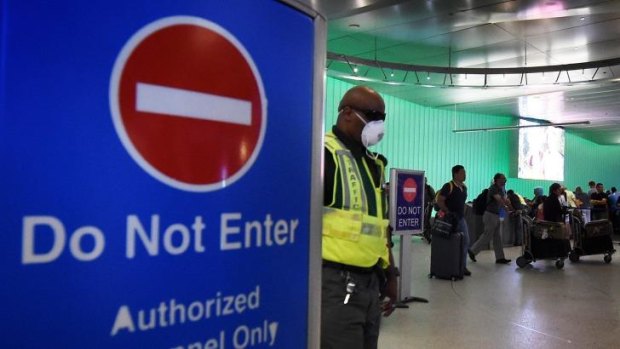 An airport worker in the arrivals area of Los Angeles International Airport. The US announced increased passenger screenings for Ebola on Thursday, followed swiftly by Britain.