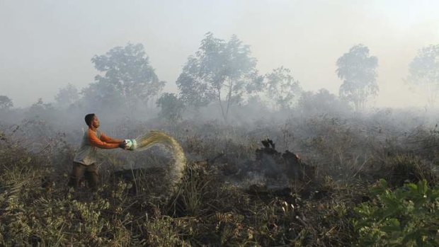 A resident tries to extinguish fire on the outskirt of Pekanbaru in Indonesia's Riau province.