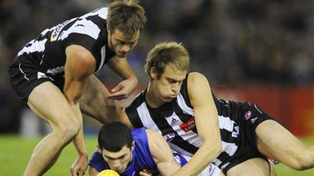 Bulldog Jarrad Grant is hemmed in by Magpie rivals Alan Toovey  and Ben Reid at Etihad Stadium yesterday.