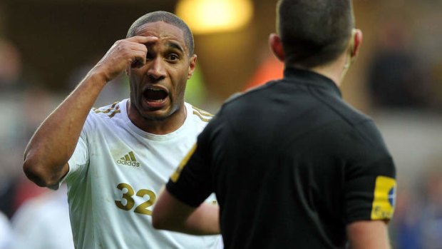 Swansea's Ashley Williams gestures after being booked by referee Michael Oliver.