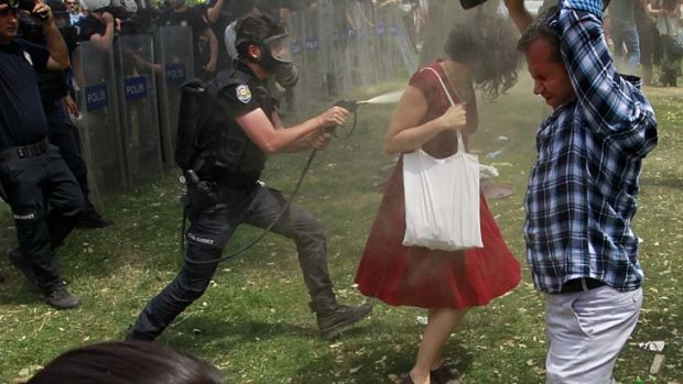 The riot policeman sprays Ceyda Sungur from up close.