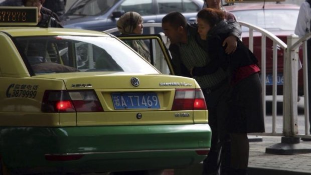 Ilham Tohti's wife Guzaili Nu'er is helped into a taxi after the verdict.