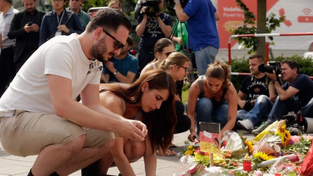 People lay flowers and candles outside the OEZ shopping centre. 