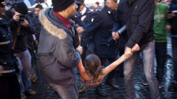 A Femen activist is detained by Italian police officers following a protest against the Pope while the papal conclave was sitting.