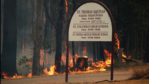 Close call: Fire licks the sign outside St Thomas Aquinas Primary School.