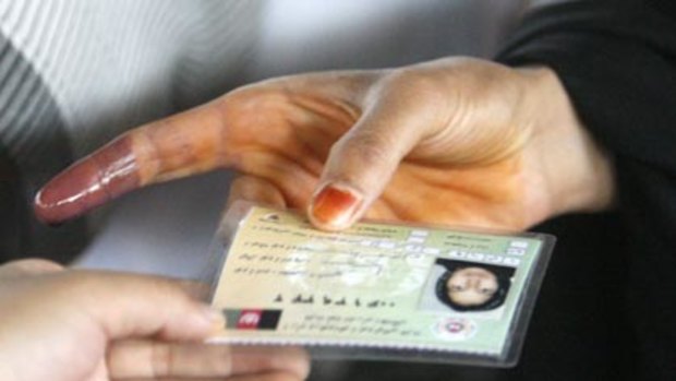 "Completely delible"...a woman show an ink-stained finger as she hands over her ID card at a polling station in Kabul.